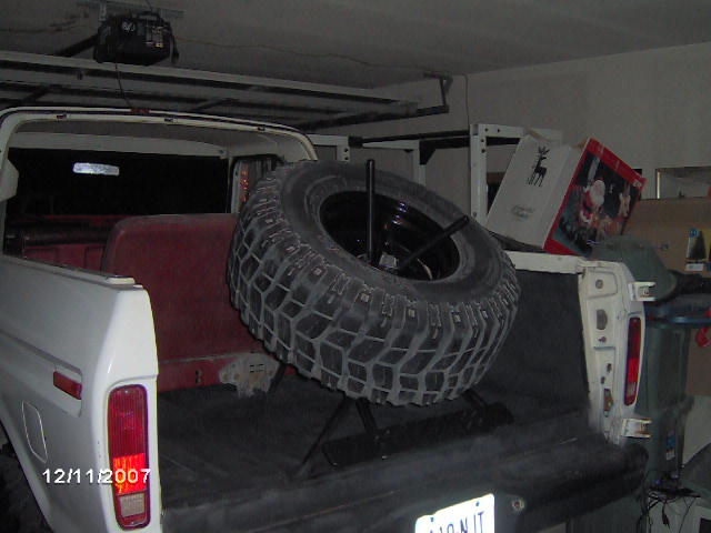 Rear of a white 1978 Ford Bronco with a spare tire mounted inside the bed. Red seats visible