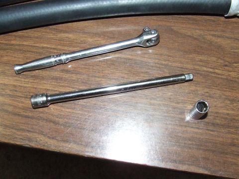 2003 Ford Crown Victoria - Tools are laid out on a wooden surface, with a black hose in the background.