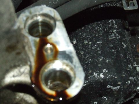 2003 Ford Crown Victoria - Close-up of a metal engine component showing oil residue around two ports.