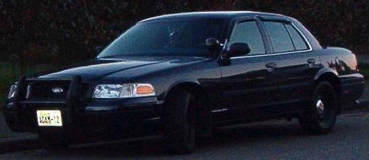 Black Ford Crown Victoria sedan with push bar and blacked-out steel wheels