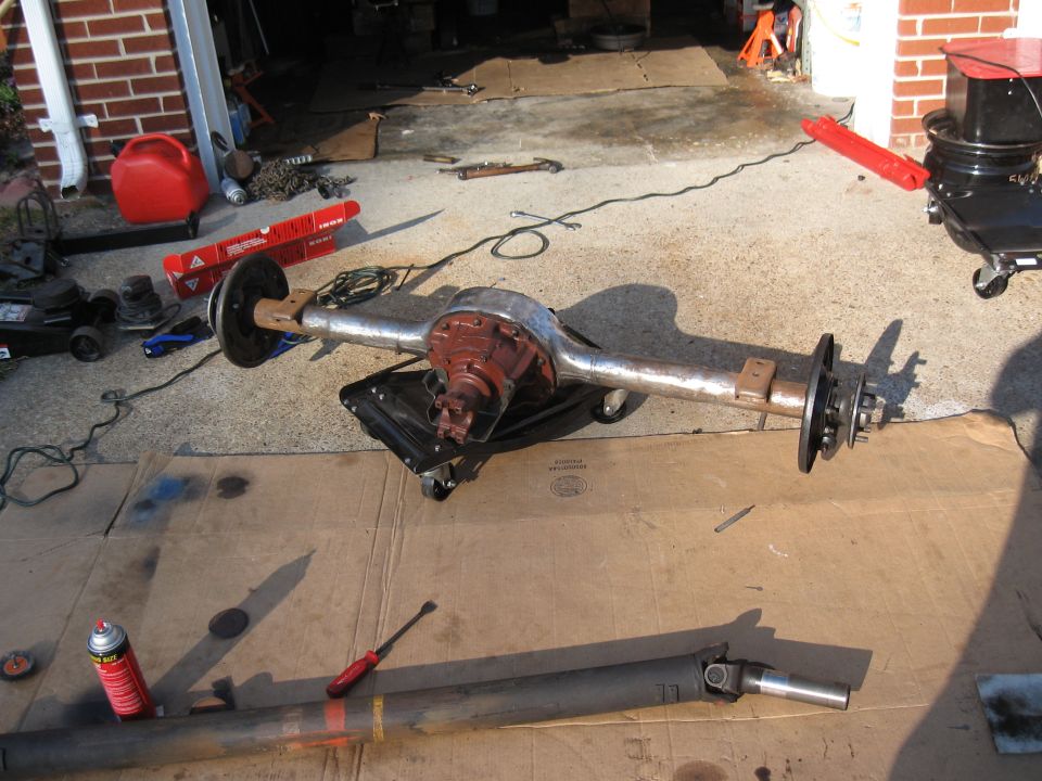Rear axle assembly and driveshaft on garage floor with tools