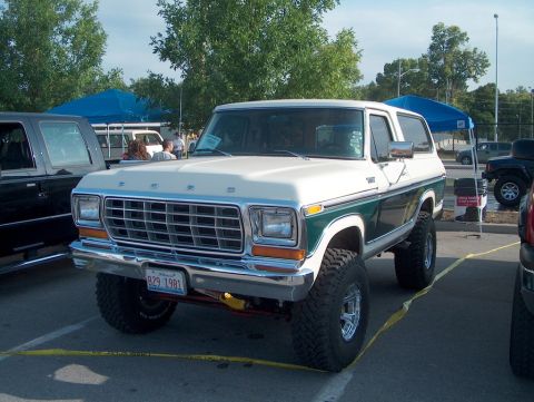 1979 Ford Bronco - This lifted 1979 Ford Bronco features a two-tone paint scheme and is parked outdoors with other vehicles present.