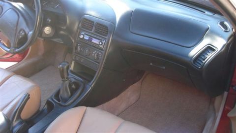 1996 Ford Probe - The interior of a car shows tan seats, dashboard, and center console with a gear shifter.