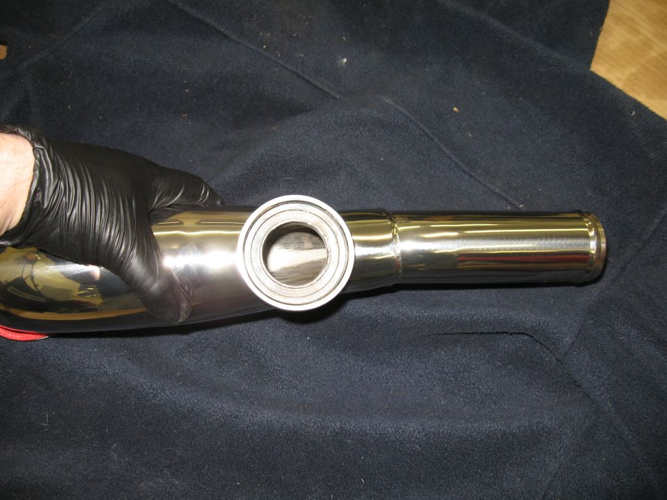 Chrome exhaust pipe held by gloved hand on dark fabric
