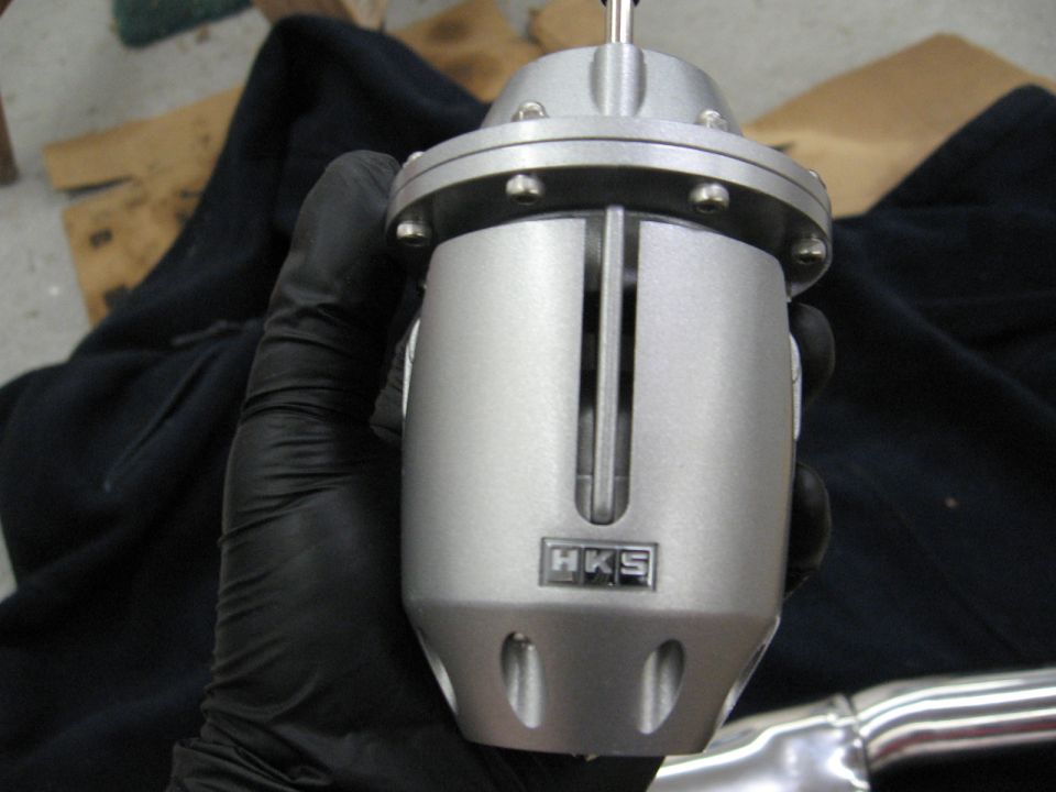 HKS blow-off valve held in a black gloved hand