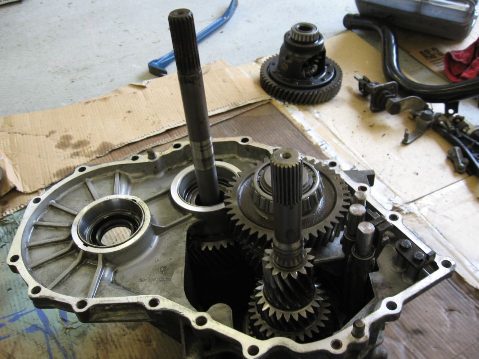 Transmission gears and differential inside an open casing on a cardboard-covered floor