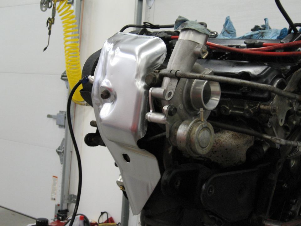 Engine component with shiny metal heat shield attached to turbocharger