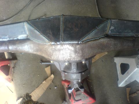 1985 Ford Bronco - Custom metalwork is welded onto a vehicle's rear axle assembly, which is elevated on jack stands.