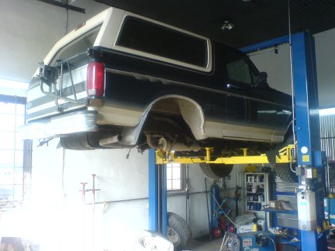 1985 Ford Bronco - A black and white 1985 Ford Bronco is shown on a hydraulic lift in a workshop setting.