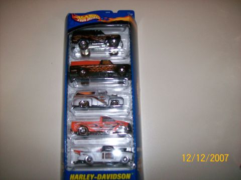 1979 Ford Bronco - A sealed Hot Wheels Harley-Davidson five-car gift pack photographed on a plain wall, with five die-cast trucks and hot rods stacked in the…