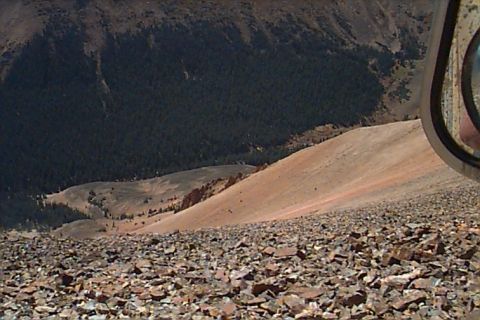 1994 Ford Bronco - A view from a vehicle's perspective looking down a steep, rocky mountainside into a valley with a forested valley below.