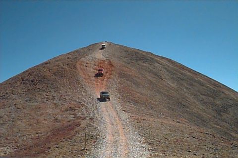 1994 Ford Bronco - Multiple SUVs ascend a treacherous mountain path, off-road capability on a clear day.