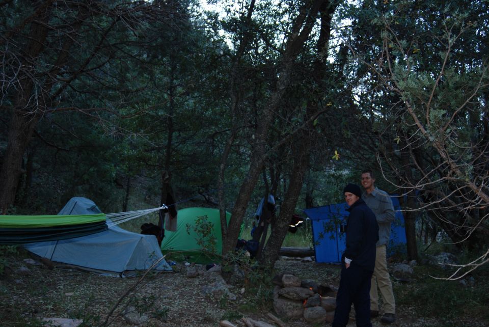 Campsite with tents, a hammock, and two people standing near a fire pit