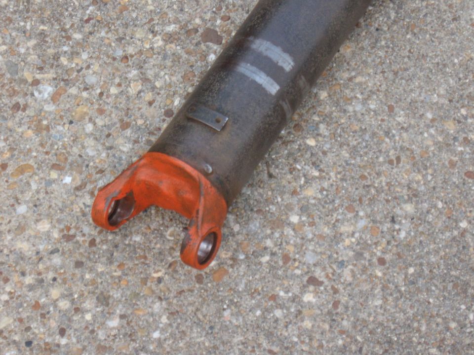 Close-up of a driveshaft yoke with orange paint on the U-joint ears. Two white marks are visible on the shaft