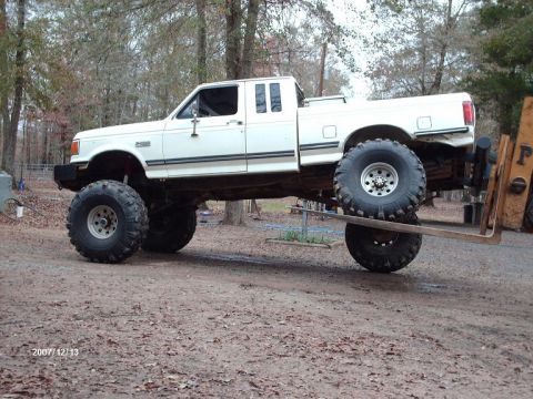1990 Ford F-150 - This modified 1990 Ford F-150 features a lifted suspension and massive off-road tires, giving it an imposing stance.