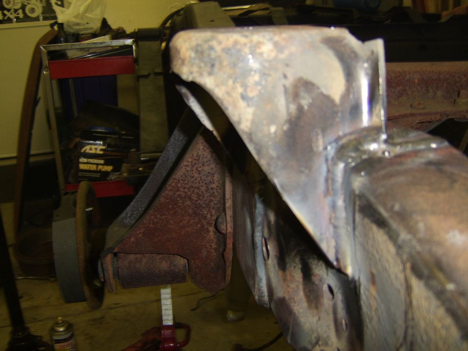 Close-up of welded sheet metal bracket on rusty truck frame during restoration in a garage