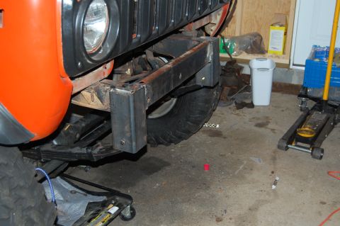1994 Ford Bronco - Close-up view of an orange fender and a custom-fabricated front bumper assembly on a vehicle, possibly undergoing modifications.