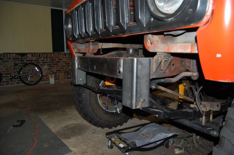 1994 Ford Bronco - Close-up of a custom front bumper being installed on an orange vehicle, showing suspension components.