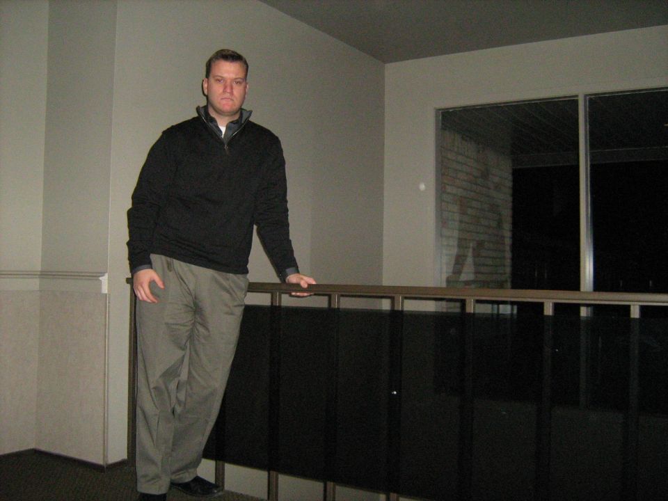 Man in black pullover standing by an indoor railing