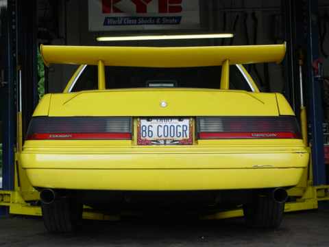 1986 Mercury Cougar - Yellow 1986 Mercury Cougar LS with a prominent rear spoiler and custom license plate '86 COOGR'.