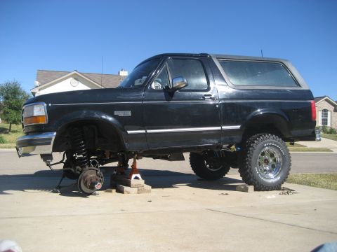 1994 Ford Bronco - 1994 Ford Bronco undergoing front-end maintenance with wheels off.