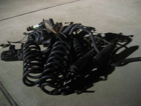 1994 Ford Bronco - A collection of vehicle suspension components, including coil springs and shock absorbers, are laid out on a concrete surface.