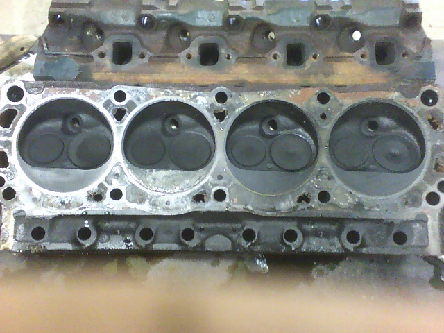 Engine cylinder head with four cylinders visible, showing valves and combustion chambers