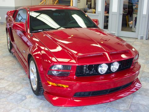 2008 Ford Mustang - A red Ford Mustang is parked inside a building with a showroom feel.