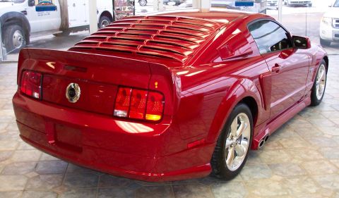 2008 Ford Mustang - Rear view of a red coupe with distinctive horizontal louvers covering the rear window.