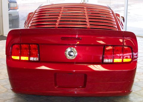2008 Ford Mustang - The rear of a red Ford Mustang is shown, louvers and a chrome emblem.