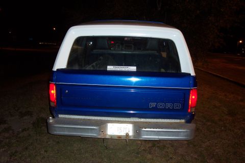 1984 Ford Bronco - Rear view of a blue and white Ford Bronco, with "FORD" branding visible on the tailgate.