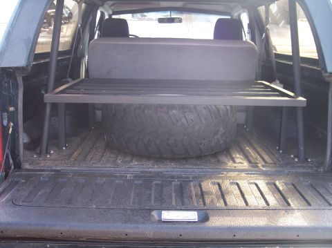 1995 Ford Bronco - Rear interior view of a 1995 Ford Bronco with a spare tire and a custom metal storage rack installed.