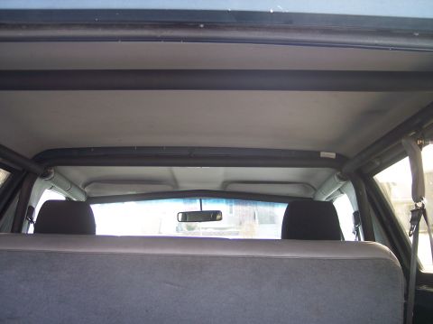 1995 Ford Bronco - The interior of the vehicle shows a roll cage installed over the rear seats and headliner.