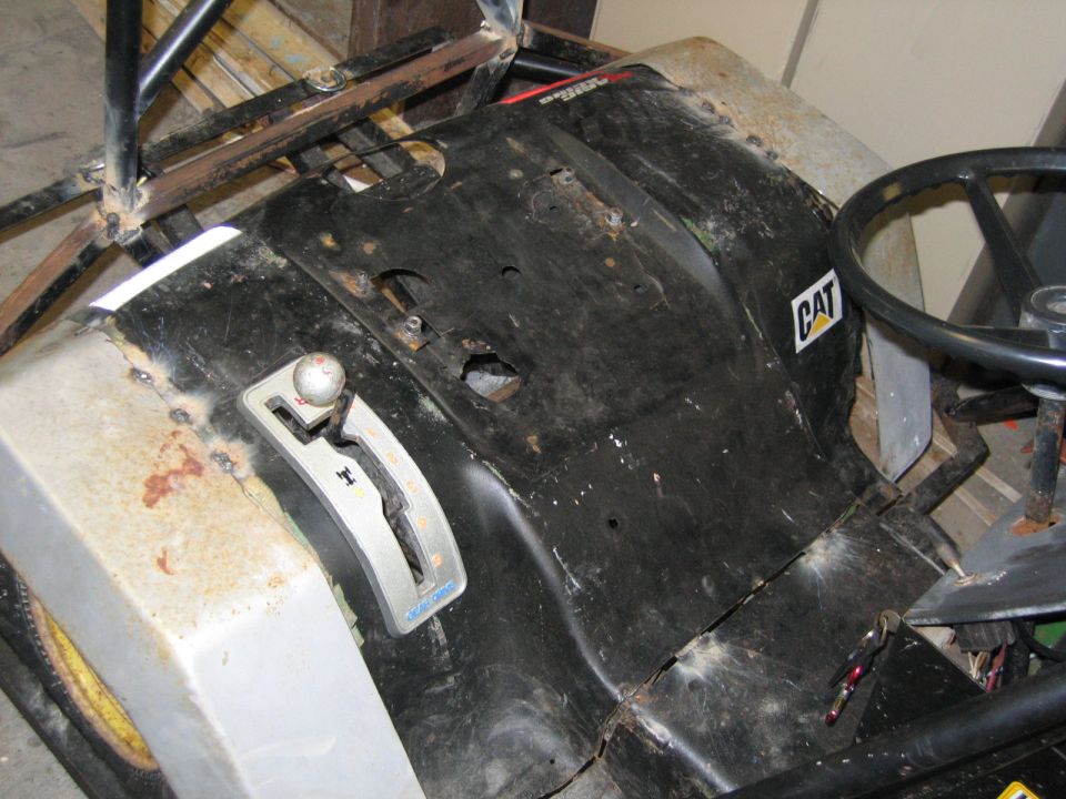 Driver area of a CAT-branded riding mower or kart showing seat pan and shifter