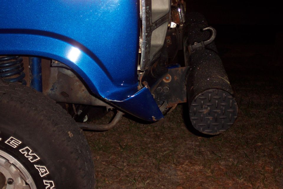 Close-up of front fender and tire on a blue vehicle with a black bumper accessory