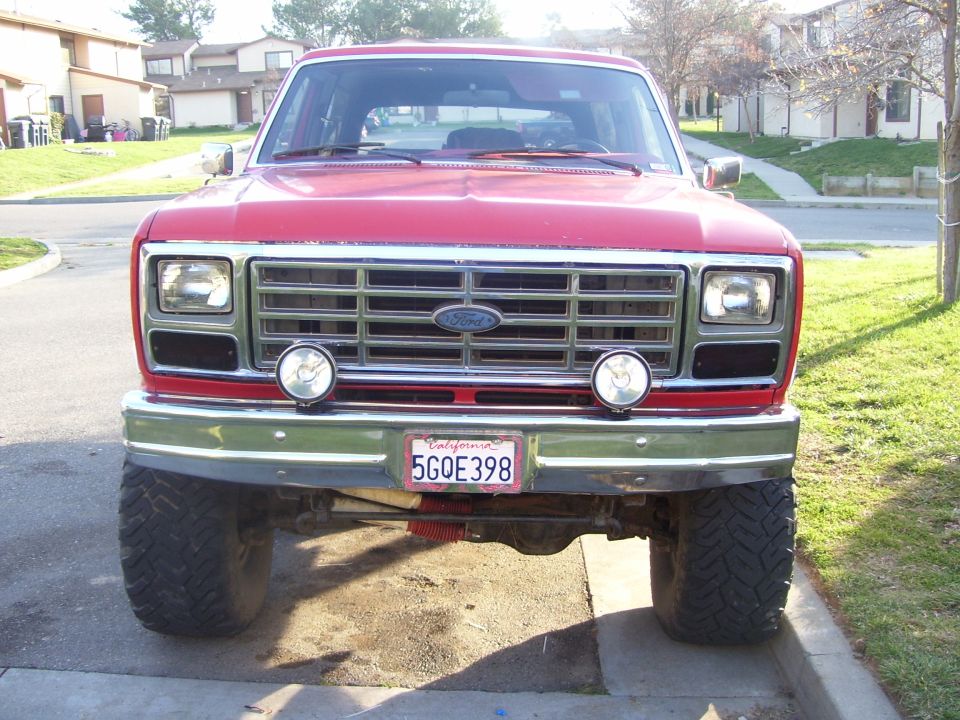 Front view of a red Ford Bronco with a chrome grille and aftermarket lights. California license plate 5GOE398 is visible