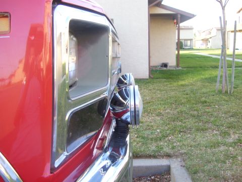 1986 Ford Bronco - Close-up of the side of a red 1986 Ford Bronco, highlighting its fender and chrome accents.