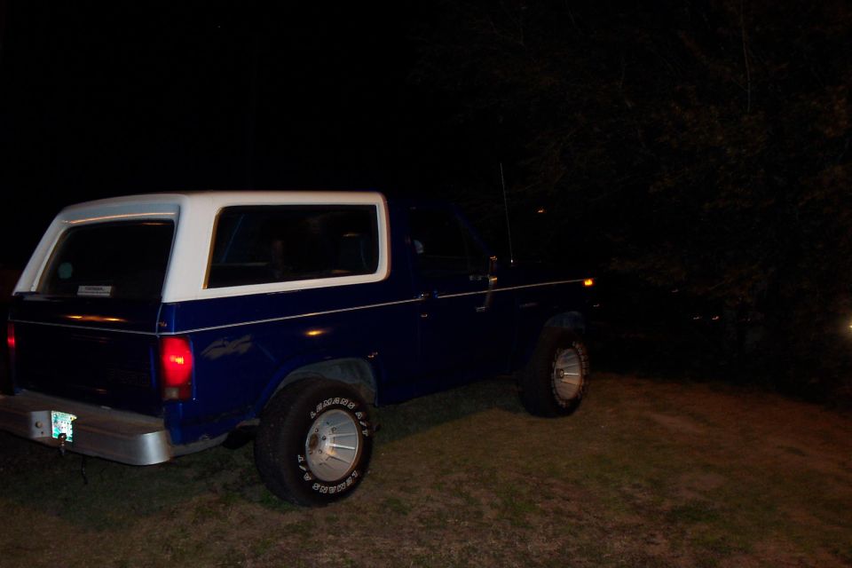 Blue and white SUV from the rear-left, parked on grass at night