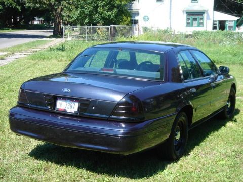 1999 Ford Crown Victoria - This Ford Crown Victoria has a dark blue paint job and black steel wheels. The rear taillights appear to be tinted.