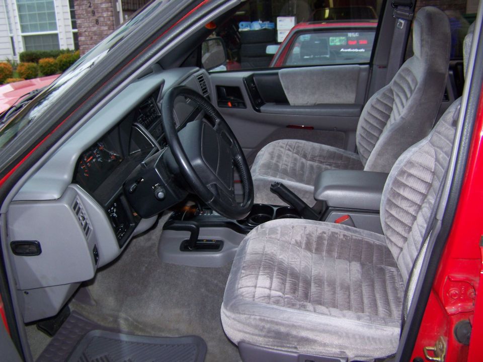 Interior of a red 1994 Jeep Grand Cherokee showing gray velour seats and dashboard