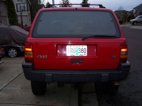 1994 Jeep Grand Cherokee - The rear of a red Jeep Grand Cherokee is shown, its license plate and taillights.