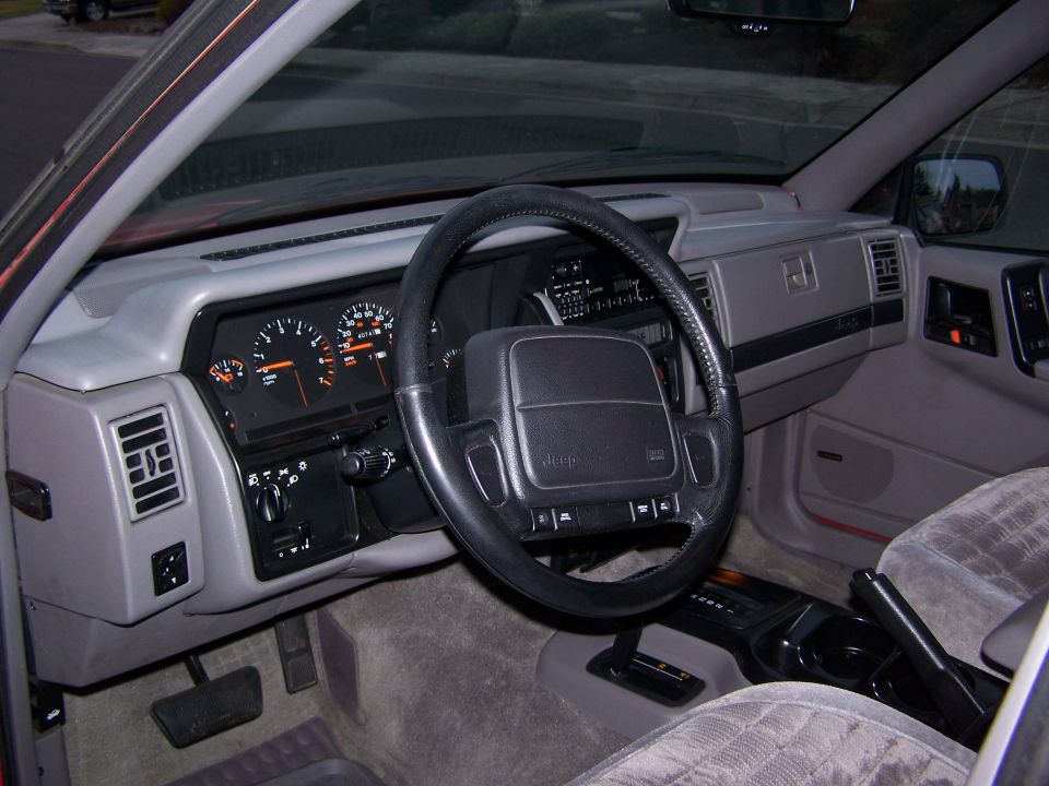 Interior shot of a Jeep SUV, showing the dashboard, steering wheel with Jeep logo, and center console