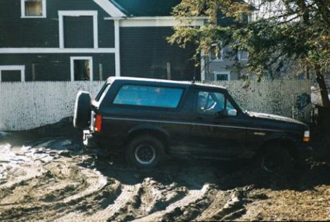 1995 Ford Bronco - A black 1995 Ford Bronco is seen in a muddy area with a spare tire mounted on the back.