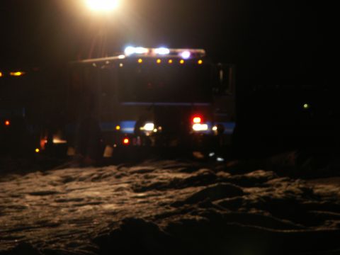 1984 Ford Bronco - A dark truck is seen from the rear at night, illuminated by its own emergency lights.