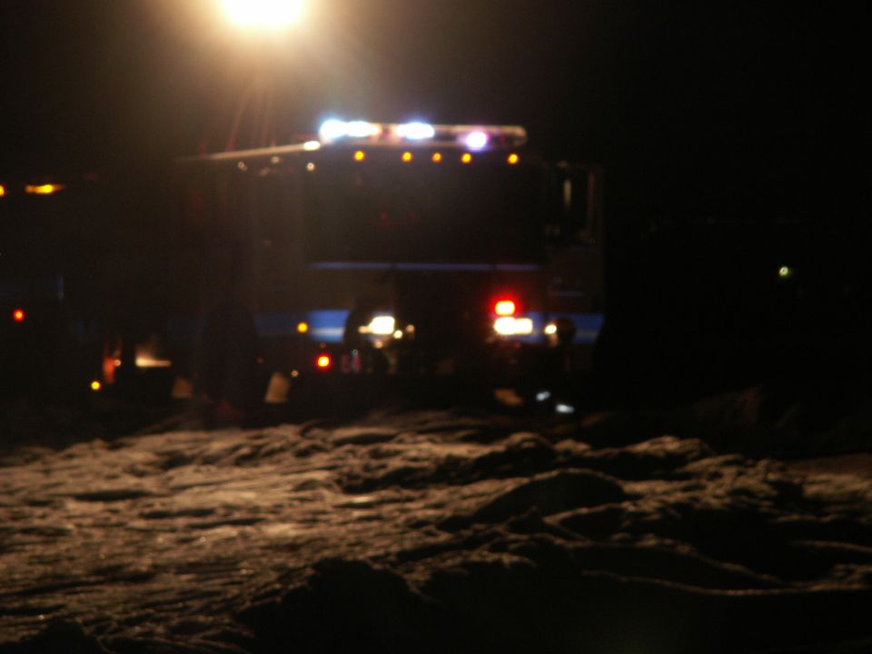 Rear view of a dark truck with flashing emergency lights at night