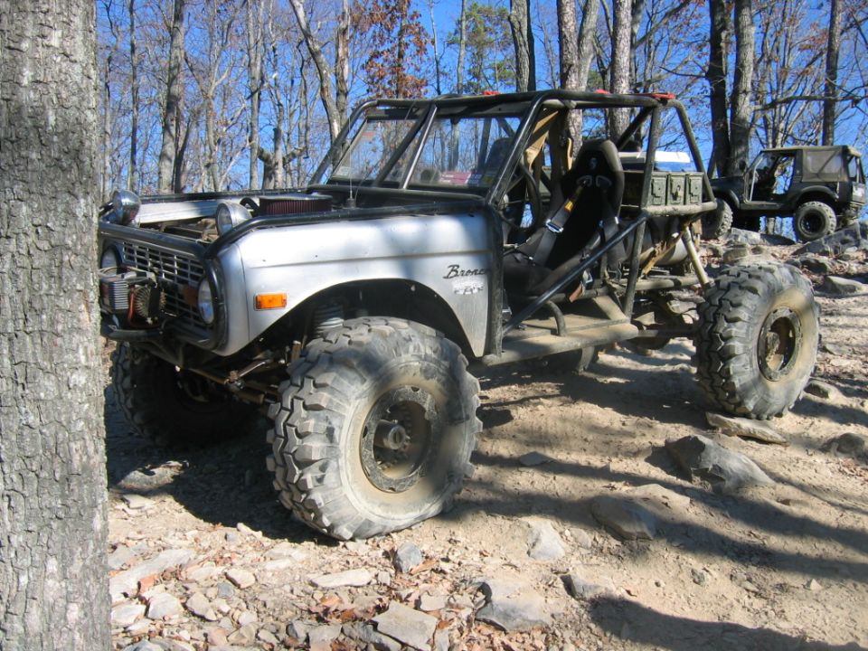 Modified 1970 Ford Bronco buggy with roll cage and large tires, another similar vehicle behind it