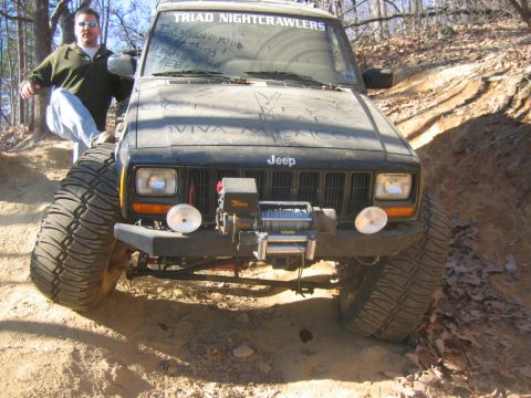 1992 Ford Mustang - A man poses with his modified Jeep Cherokee XJ on an off-road trail.
