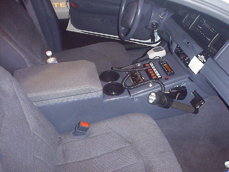 Gray police car interior with center console radio, flashlight mount and cup holders