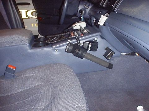 2002 Ford Crown Victoria - The interior console of a 2002 Ford Crown Victoria shows police radio equipment and a mounted flashlight.