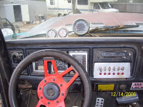 1978 Ford Bronco - The interior of a vehicle shows a custom steering wheel, multiple gauges, and a panel of switches.